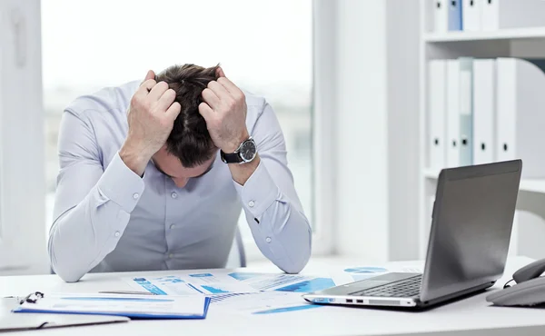 Stressad affärsman med papper i office — Stockfoto