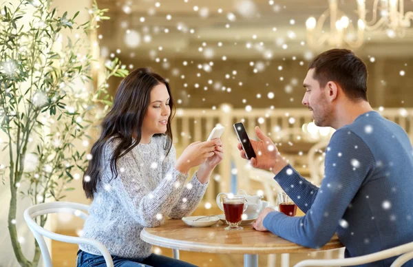 Счастливая пара со смартфонами пьет чай в кафе — стоковое фото