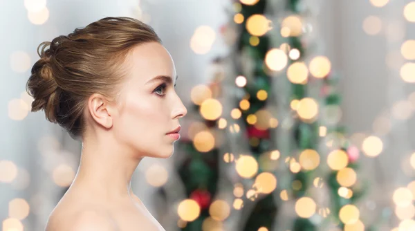 Beautiful young woman face over christmas lights — Stock Photo, Image