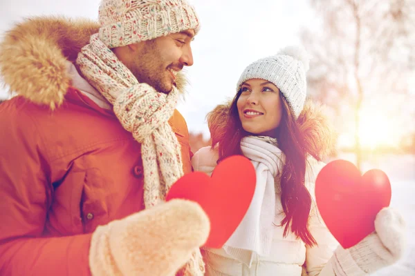 Šťastný pár s červenými srdci nad zimní krajina — Stock fotografie