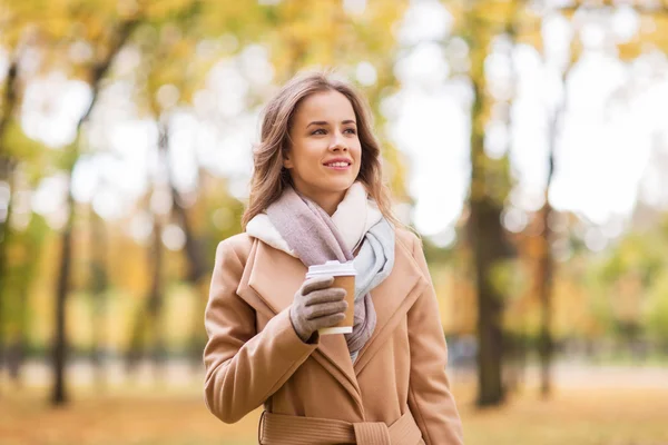 幸福的年轻女人，在秋天的公园里喝咖啡 — 图库照片
