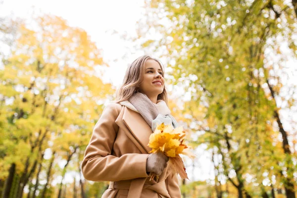 Красива жінка з кленовим листям в осінньому парку — стокове фото