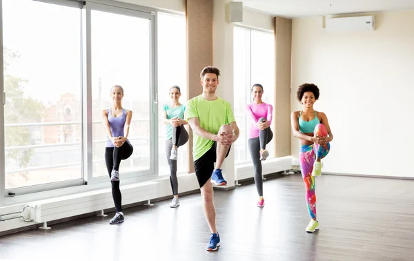 Gruppe lächelnder Menschen, die im Fitnessstudio trainieren — Stockfoto