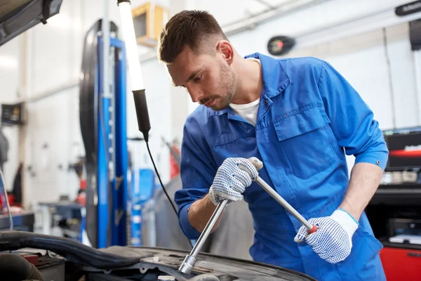 Meccanico con chiave inglese che ripara auto in officina — Foto Stock