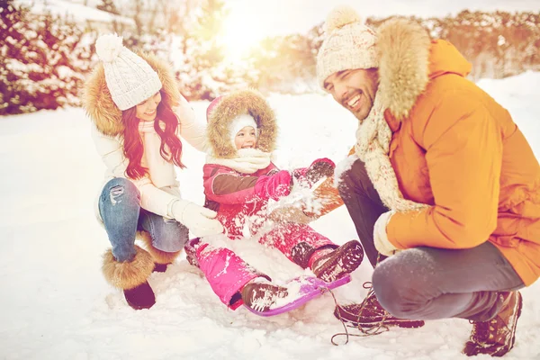 Счастливая семья с ребенком на санях, весело проводящая время на свежем воздухе — стоковое фото