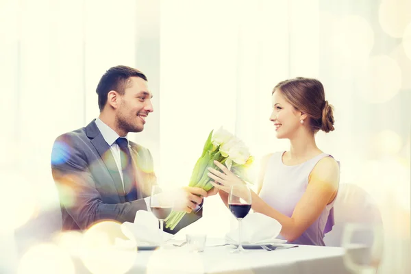 Lächelnder Mann überreicht Blumenstrauß im Restaurant — Stockfoto
