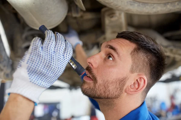 Mecânico homem com lanterna reparação carro na loja — Fotografia de Stock