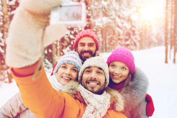 Smiling friends with camera in winter forest — Stock Photo, Image