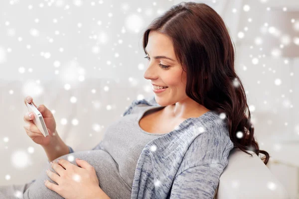 Ευτυχισμένη έγκυος γυναίκα με smartphone στο σπίτι — Φωτογραφία Αρχείου