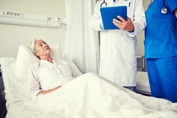 Médico e enfermeira visitando mulher idosa no hospital — Fotografia de Stock