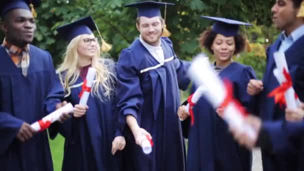 Estudiantes felices en morteros con diplomas — Vídeos de Stock