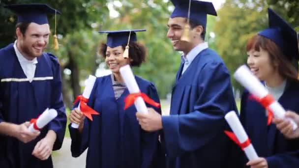 Estudiantes felices en morteros con diplomas — Vídeos de Stock