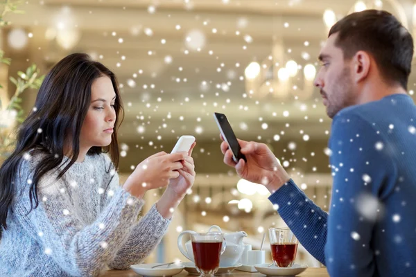 Пара со смартфонами пьют чай в кафе — стоковое фото