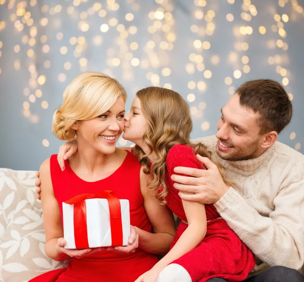 Happy family with christmas gift kissing — Stock fotografie