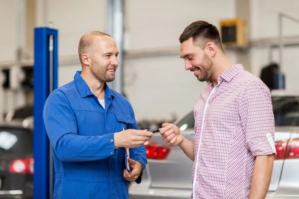 Bilmekaniker som ger nyckeln till mannen på bil shop — Stockfoto