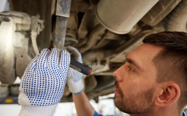 Mechaniker mit Taschenlampe repariert Auto im Geschäft — Stockfoto