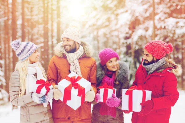 Gelukkige vrienden met gift boxes in winter forest — Stockfoto