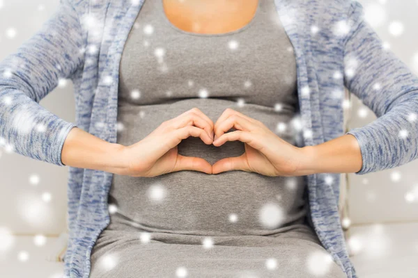 Закрыть глаза на счастливую беременную женщину, делающую сердце — стоковое фото