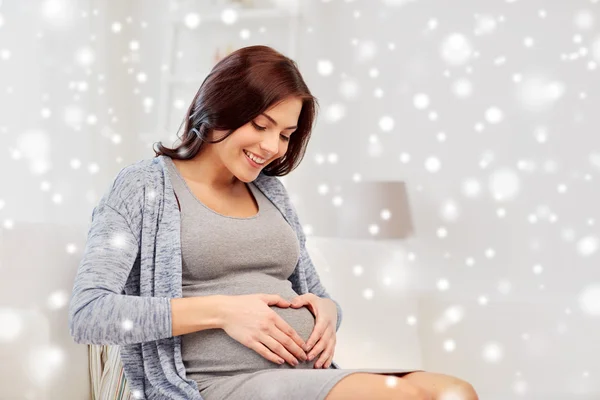 Feliz embarazada haciendo gesto de corazón en casa — Foto de Stock