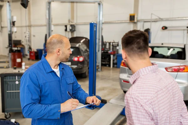 Meccanico con appunti e uomo in officina — Foto Stock