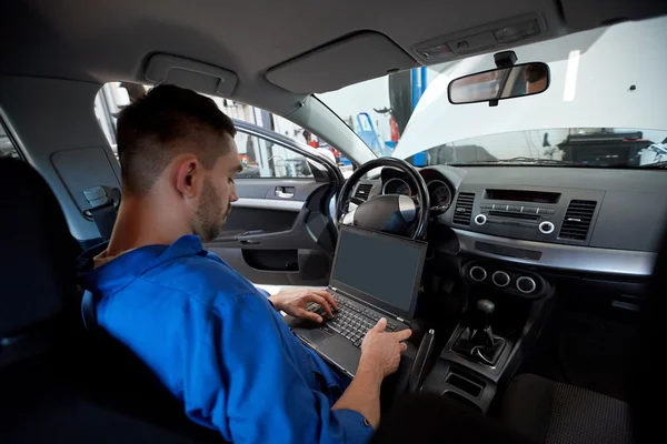 Hombre mecánico con el ordenador portátil que hace el diagnóstico del coche —  Fotos de Stock