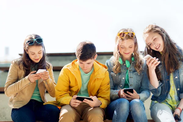 Amigos adolescentes felices con teléfonos inteligentes al aire libre — Foto de Stock