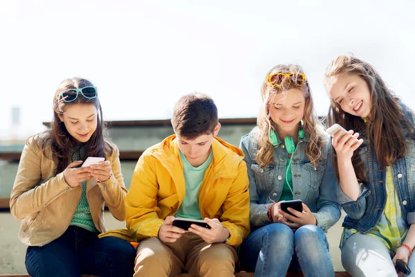 Happy teenage friends with smartphones outdoors Stock Picture