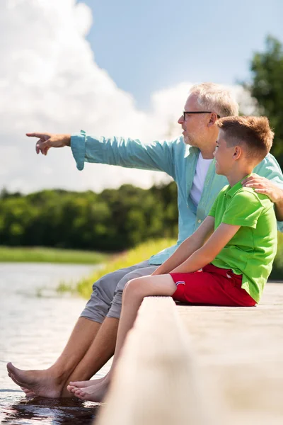 Grootvader en kleinzoon zittend op rivierligplaats — Stockfoto