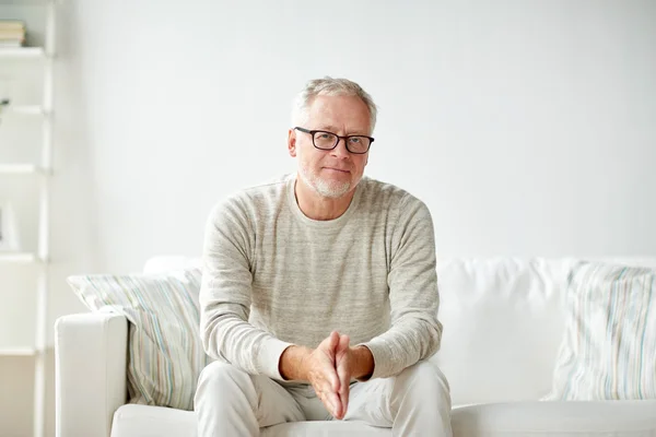 Sorridente homem sênior em óculos sentado no sofá — Fotografia de Stock