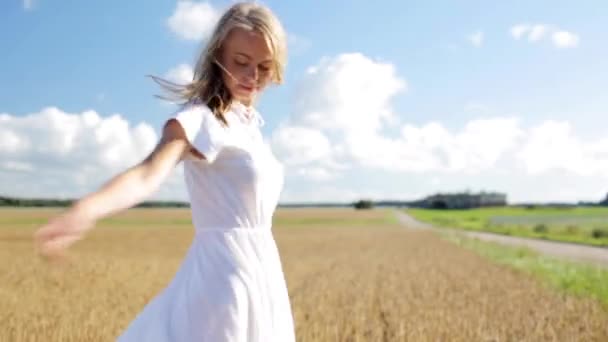 Lächelnde junge Frau im weißen Kleid auf einem Getreidefeld — Stockvideo