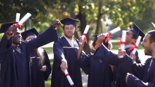 Glückliche Studenten in Mörteltafeln mit Diplomen — Stockvideo