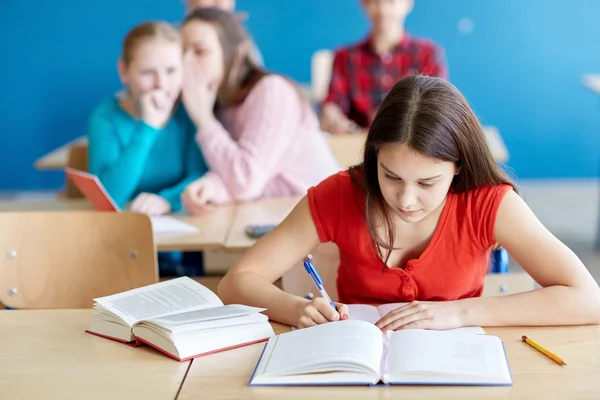 Studenter skvallra bakom klasskamrat tillbaka i skolan — Stockfoto