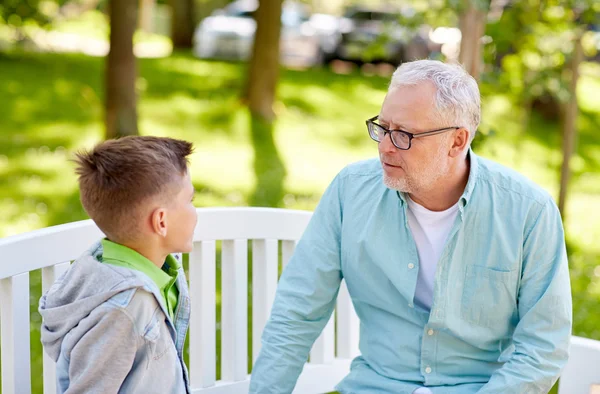 Дедушка и внук разговаривают в летнем парке — стоковое фото