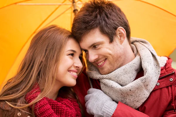Усміхнена пара з парасолькою в осінньому парку — стокове фото