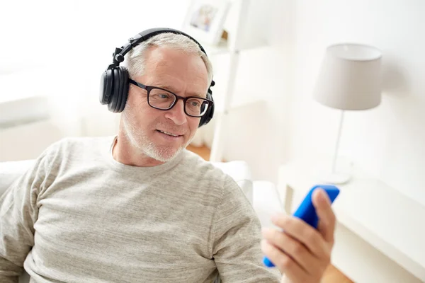 Homem sênior feliz com smartphone e fones de ouvido — Fotografia de Stock