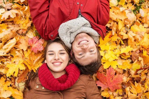 Close up of smiling couple lying on autumn leaves — Stock Photo, Image