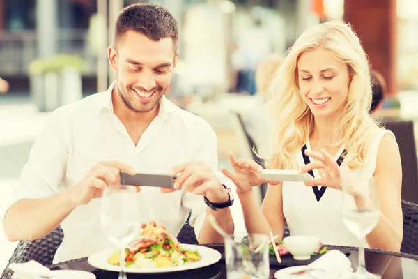 Lyckliga par med smatphone fotografera mat — Stockfoto