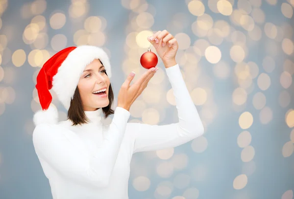 Gelukkig vrouw in santa hoed met kerstbal — Stockfoto