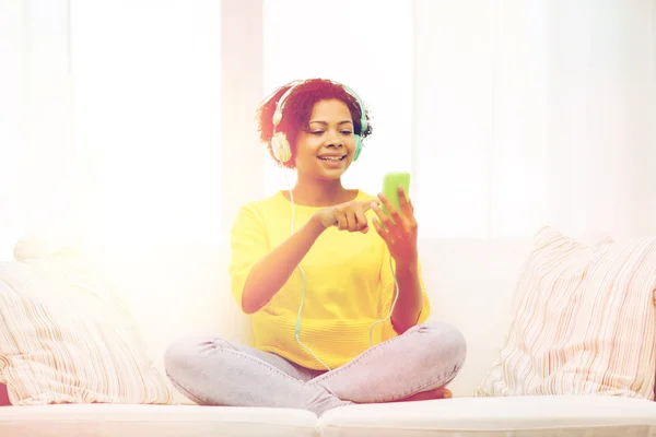 Mujer africana feliz con teléfono inteligente y auriculares —  Fotos de Stock