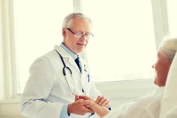 Doctor checking senior woman pulse at hospital — Stock Photo, Image