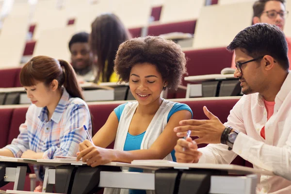 Grupo de estudiantes con cuadernos en la sala de conferencias — Foto de Stock