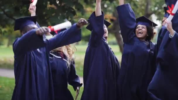 Glada studenter i murbruk styrelser med diplom — Stockvideo