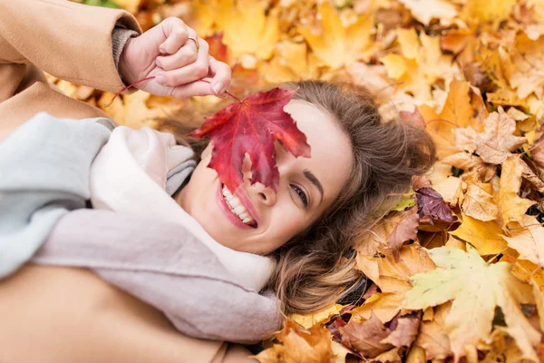 Krásná šťastná žena ležící na podzimní listí — Stock fotografie