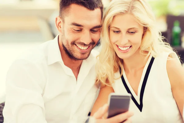 Счастливая пара со смартфоном в кафе на городской улице — стоковое фото