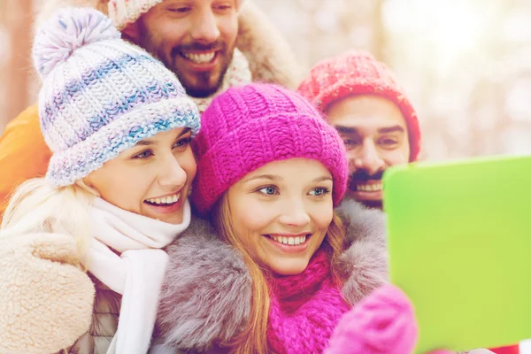 Smiling friends with tablet pc in winter forest — Stock Photo, Image