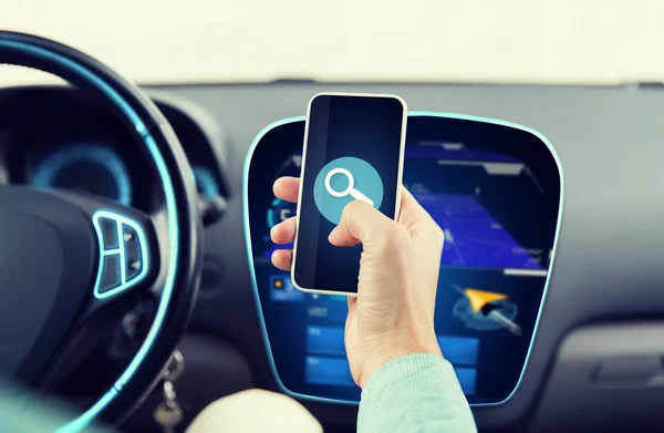 Close up of man hand with smartphone driving car — Stock Photo, Image