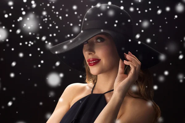 Красивая женщина в черной шляпе над снегом — стоковое фото