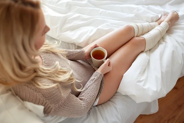 Close up of woman with tea cup in bed — Stock Photo, Image