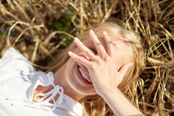 Feliz joven mujer acostada en el campo de cereales —  Fotos de Stock