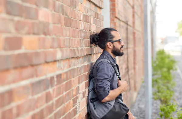 Muž s batohem stojí na městské ulici zdi — Stock fotografie